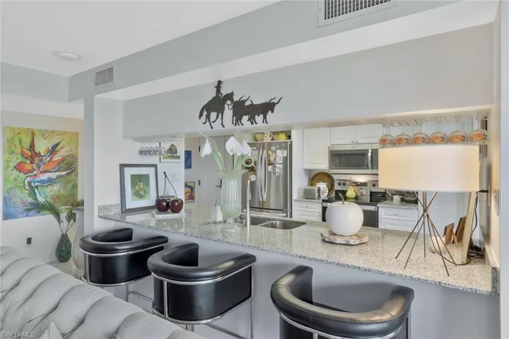Kitchen featuring a breakfast bar area, light stone counters, and white cabinets