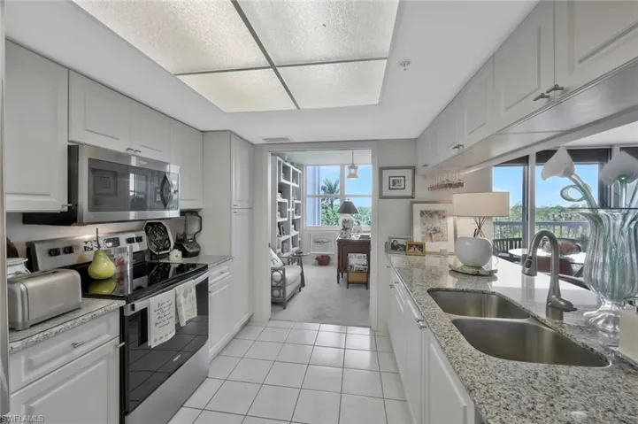Kitchen with appliances with stainless steel finishes, healthy amount of natural light, light tile patterned flooring, and white cabinetry
