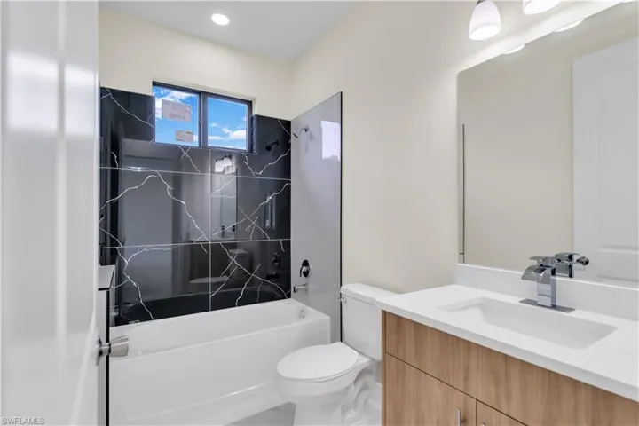 Full bathroom with vanity, tiled shower / bath combo, and toilet