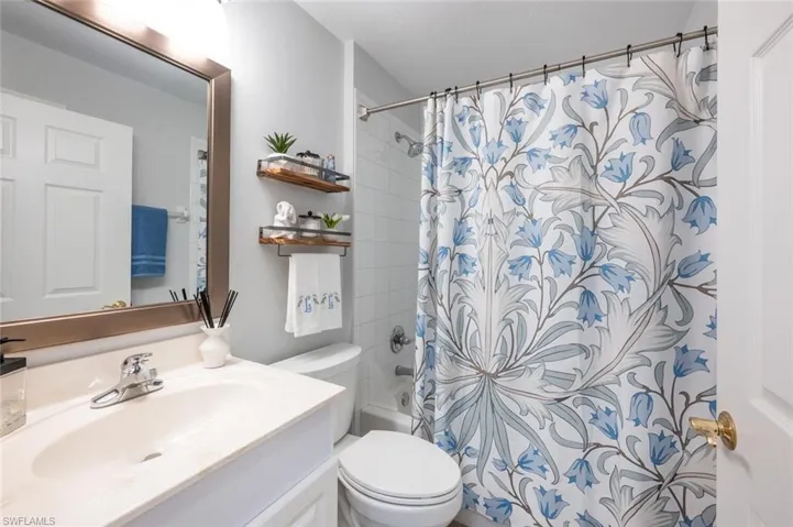 Full bathroom featuring shower / tub combo with curtain, vanity, and toilet