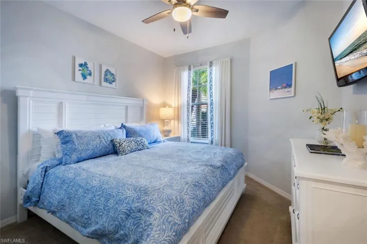 Bedroom featuring vaulted ceiling, dark carpet, a ceiling fan, and baseboards