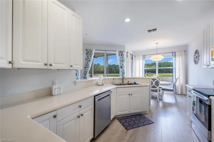 Kitchen featuring stainless steel appliances, a sink, white cabinetry, light wood-type flooring, and a wealth of natural light