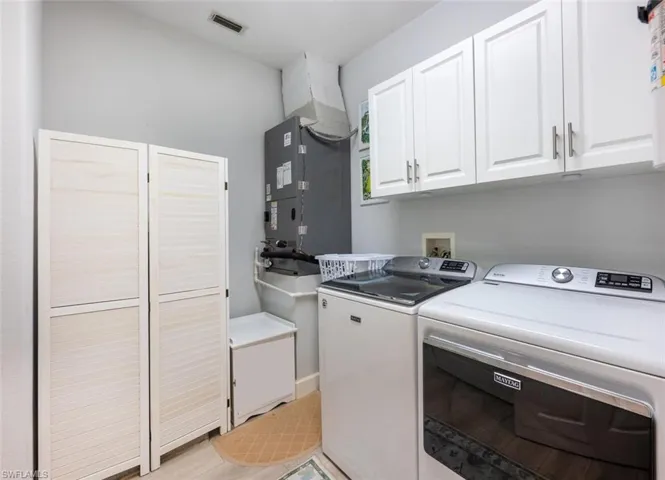 Laundry area with visible vents, heating unit, cabinet space, and washer and dryer