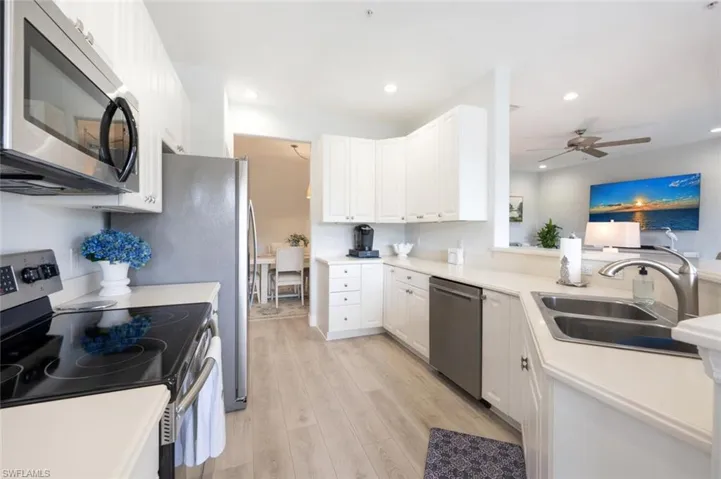 Kitchen with light wood-style flooring, recessed lighting, stainless steel appliances, a sink, and white cabinetry