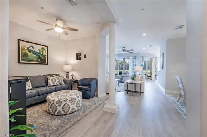 Living area with visible vents, decorative columns, baseboards, and wood finished floors