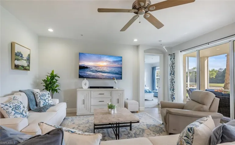Living area with recessed lighting, arched walkways, baseboards, and wood finished floors