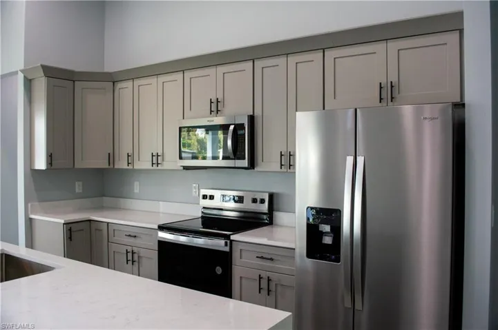 Kitchen with light stone counters, stainless steel appliances, and gray cabinetry