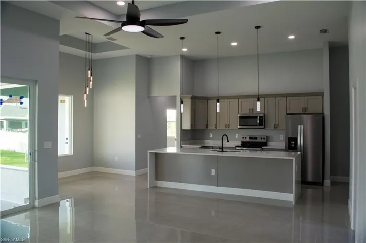 Kitchen with appliances with stainless steel finishes, a healthy amount of sunlight, and gray cabinetry