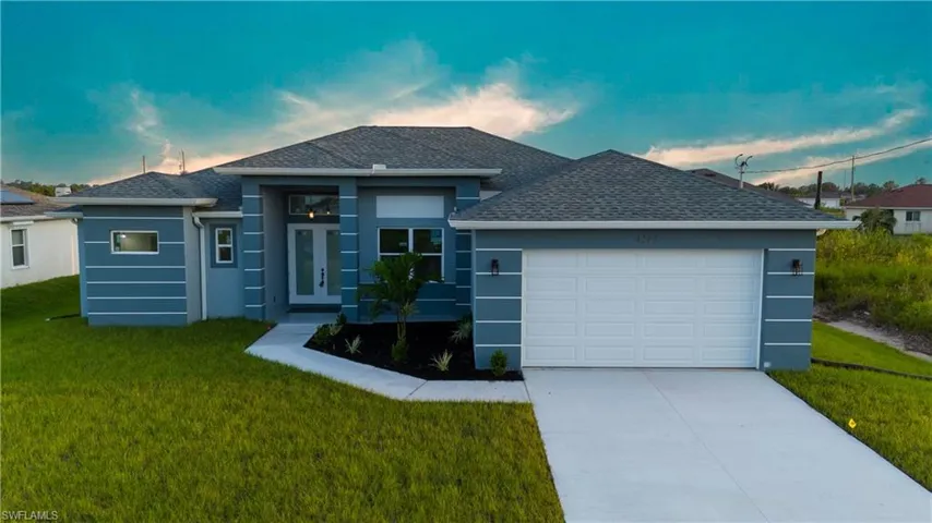 View of front of property featuring a garage and a yard