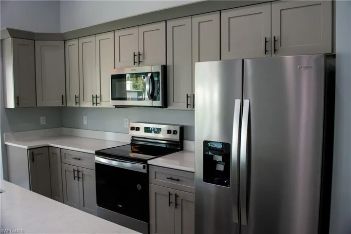 Kitchen featuring appliances with stainless steel finishes, gray cabinetry, and light stone countertops