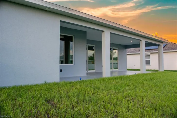 Back house at dusk featuring a yard and a patio area