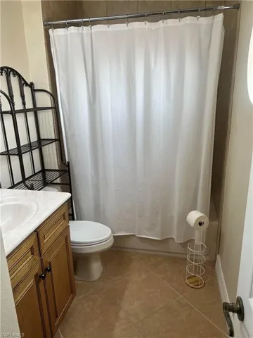 Full bathroom featuring tile floors, shower / bath combination with curtain, toilet, and vanity