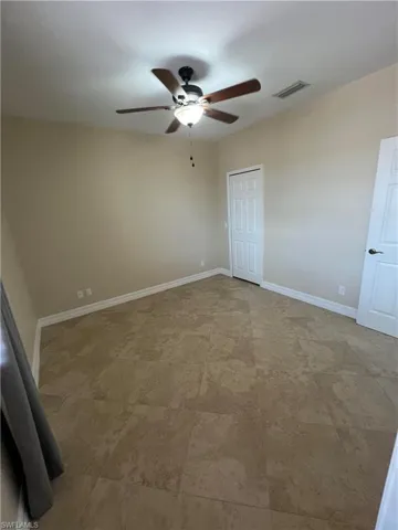 Unfurnished bedroom with ceiling fan, tile flooring, and a closet