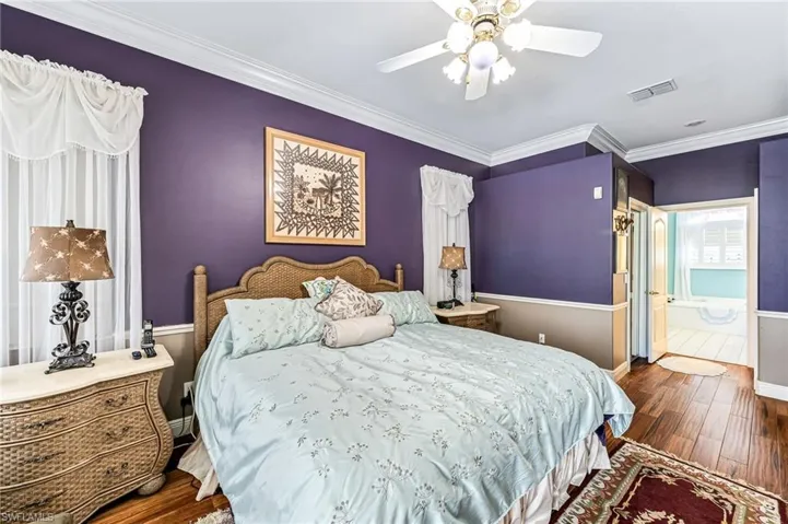 Bedroom featuring ceiling fan, crown molding, dark hardwood / wood-style flooring, and ensuite bath