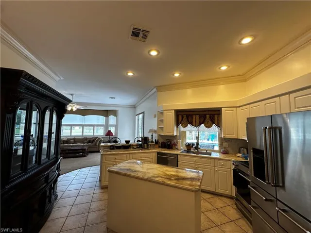 Kitchen with high quality fridge, range, ornamental molding, a peninsula, and light tile patterned floors