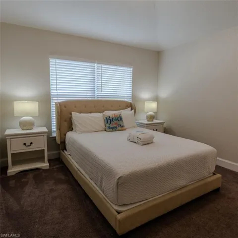 Bedroom with dark colored carpet and baseboards