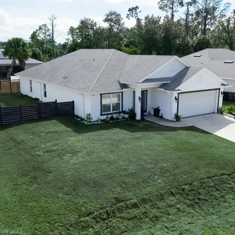 Ranch-style house featuring driveway, stucco siding, a garage, and roof with shingles