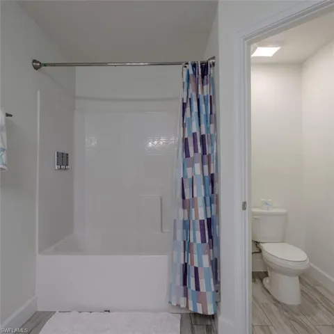 Full bathroom featuring wood finish floors and shower / tub combo
