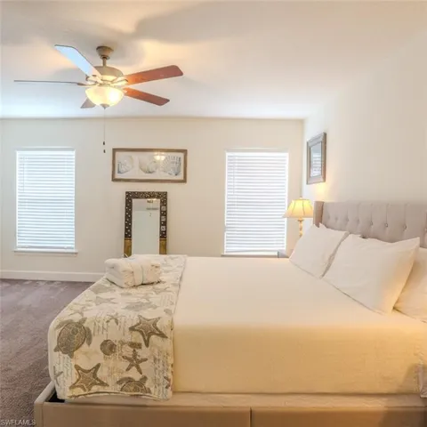 Bedroom with carpet flooring, a ceiling fan, and multiple windows
