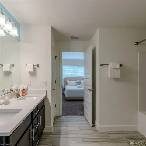 Full bath featuring double vanity, ensuite bathroom, wood finish floors, a textured ceiling, and shower / bathtub combination
