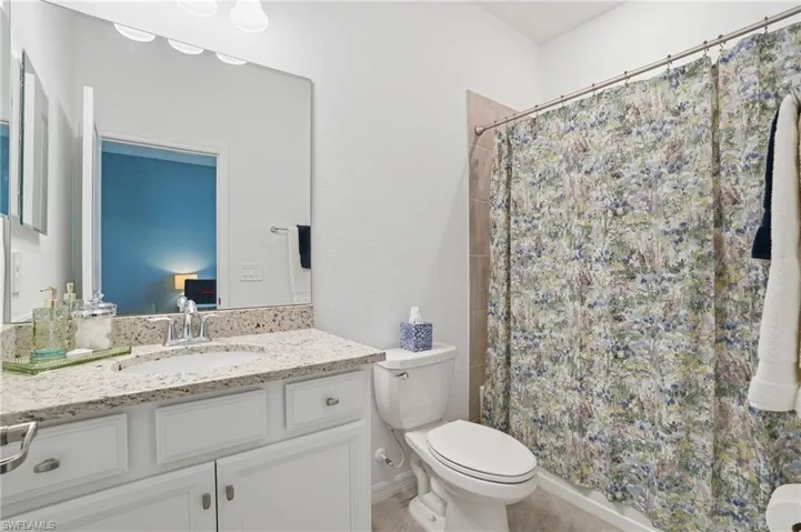 Ensuite bathroom with vanity, a shower with curtain, and light tile patterned floors