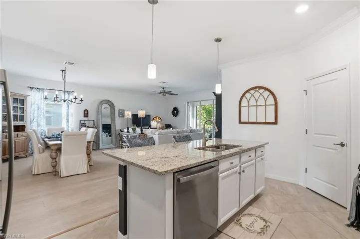 Kitchen featuring ceiling fan, white cabinetry, hanging light fixtures, light stone counters, and appliances with stainless steel finishes