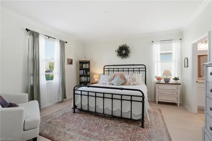 Bedroom with crown molding, multiple windows, light wood finished floors, and connected bathroom