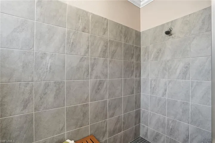 Bathroom featuring tiled shower and ornamental molding