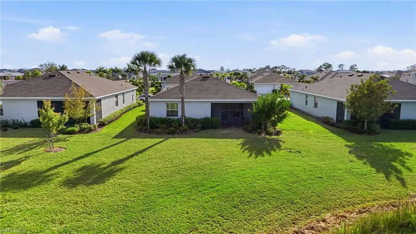 Back of house with a residential view, a sunroom, stucco siding, and a lawn