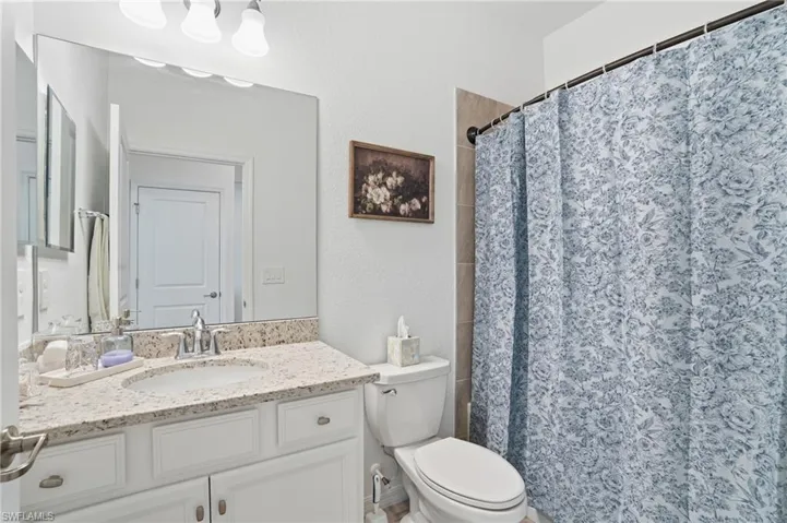 Full bath with vanity, a shower with shower curtain, and a textured wall