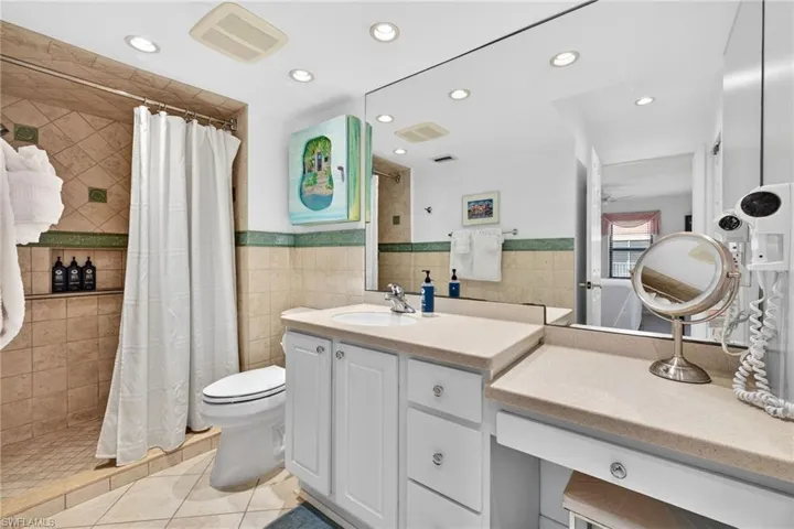 Bathroom with vanity, a shower stall, light tile patterned floors, tile walls, and recessed lighting