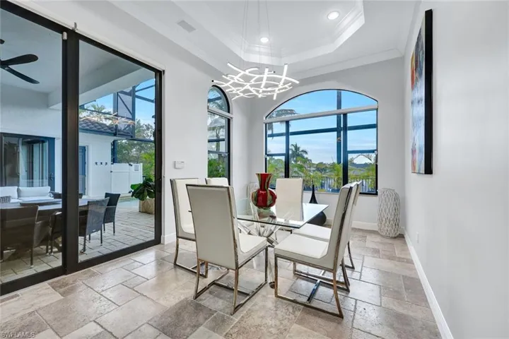 Dining space with stone tile flooring, a ceiling fan, healthy amount of natural light, crown molding, and hanging lights
