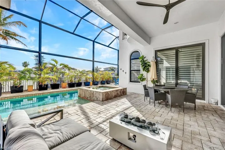 View of patio with a sunroom, a lanai, outdoor dining space, a ceiling fan, and a pool with connected hot tub