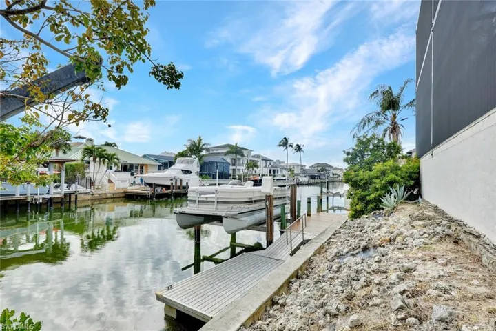 Dock featuring a water view, boat lift, and a residential view