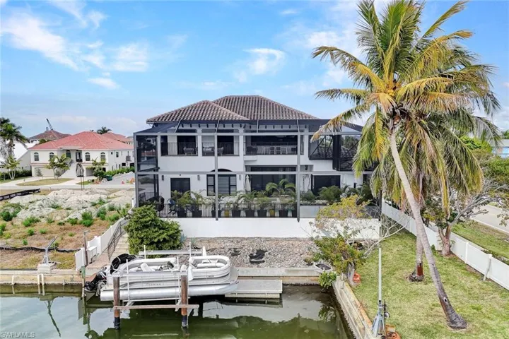 Rear view of house featuring a water view, a tiled roof, boat lift, and stucco siding
