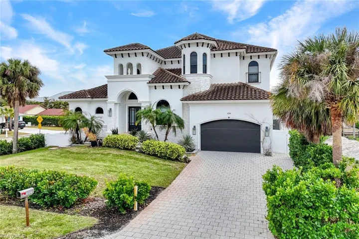 Mediterranean / spanish-style house featuring decorative driveway, stucco siding, a front lawn, a tile roof, and a garage