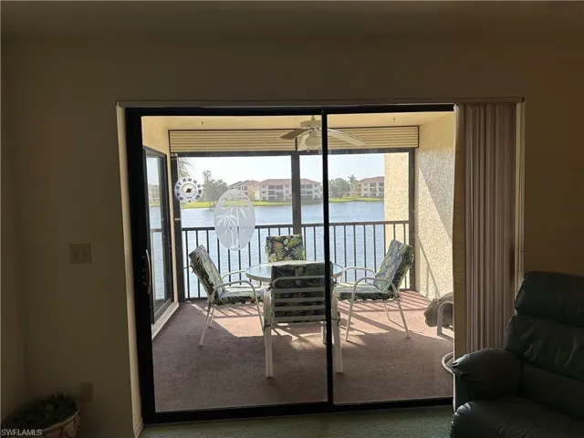 Doorway featuring dark colored carpet, a water view, and a healthy amount of sunlight