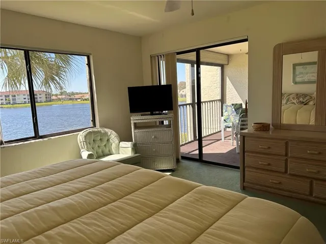 Bedroom with a water view, access to outside, and dark carpet