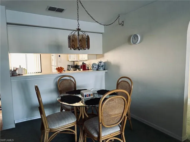 Carpeted dining space with a notable chandelier