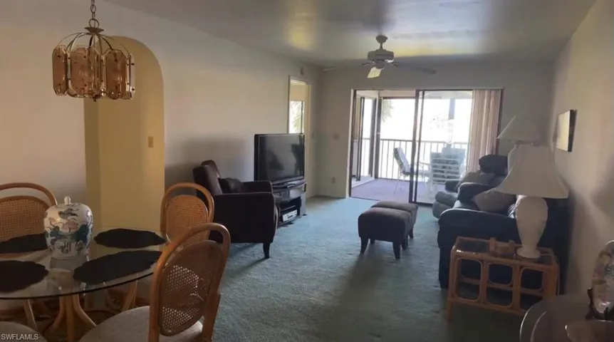 Living room featuring carpet and ceiling fan with notable chandelier