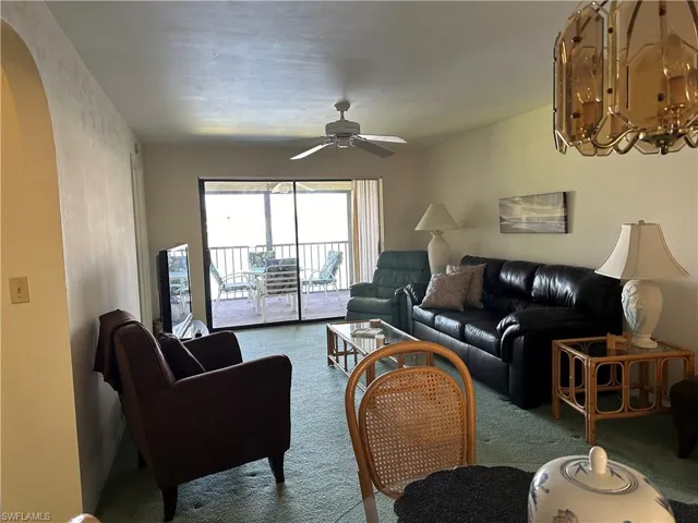 Carpeted living room with ceiling fan with notable chandelier