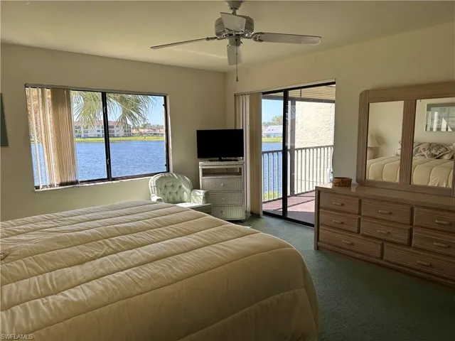 Carpeted bedroom with access to exterior, a water view, and ceiling fan
