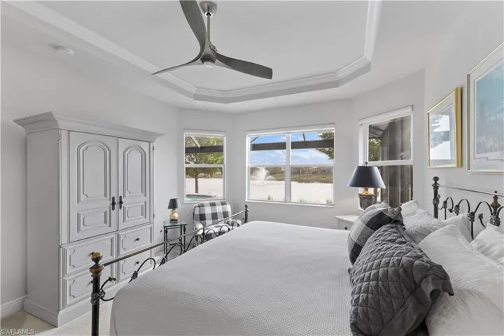 Bedroom with carpet flooring, a tray ceiling, and ceiling fan
