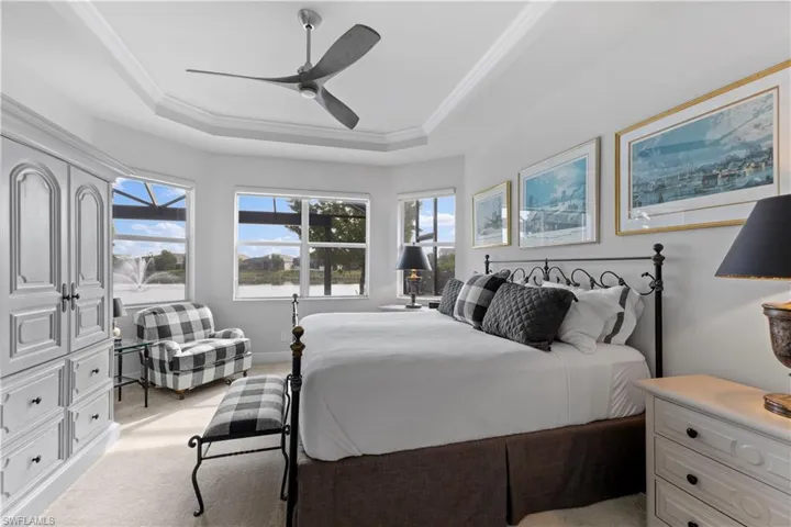 Carpeted bedroom featuring ceiling fan and a raised ceiling