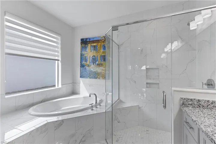 Bathroom featuring separate shower and tub and vanity