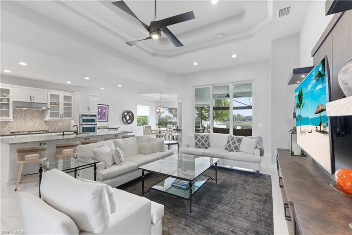 Tiled living room with ceiling fan, a raised ceiling, and a towering ceiling