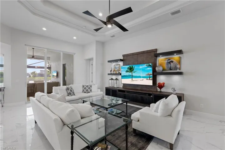 Tiled living room with a tray ceiling and ceiling fan