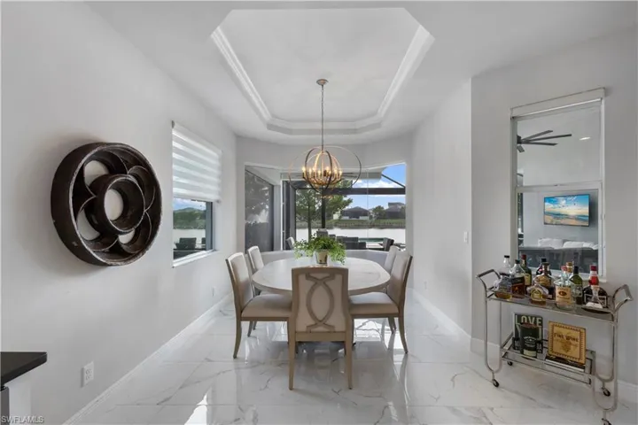 Dining space featuring beautiful chandelier, light tile patterned floors, and a tray ceiling