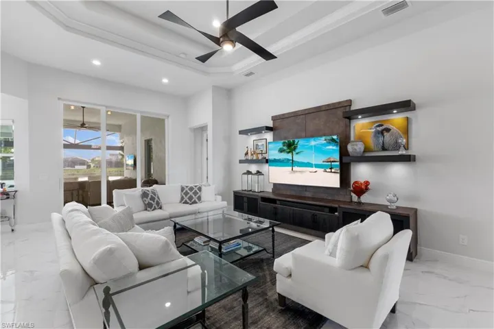 Tiled living room featuring a tray ceiling and ceiling fan
