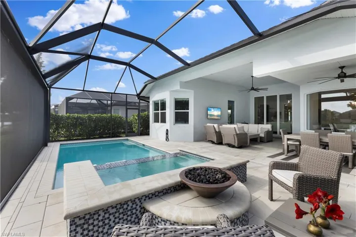 View of swimming pool with a lanai, ceiling fan, a patio area, and an outdoor fire pot!